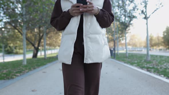 Young African American Woman Using Mobile Phone While Walking Outdoors