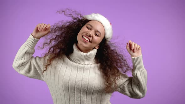 Attractive Girl in Santa Hat Celebrating Christmas or New Year on Violet Background