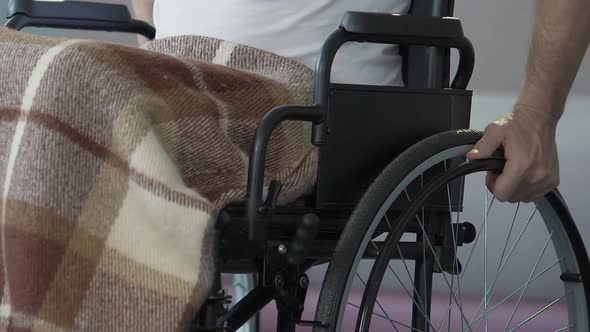 Man in wheelchair starting to push it by hands post-injury rehabilitation course