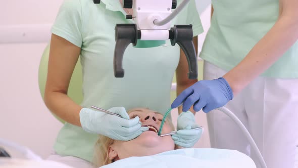 Female Dentist Examining Senior Woman Through Dental Microscope