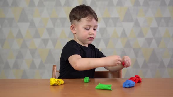 Boy of Five Years Sit at the Table and Sculpt. The Interior of the Children's Room.