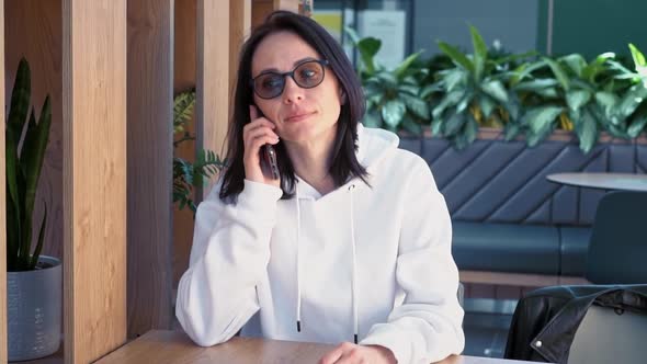 A Woman Speaks on a Mobile Phone in a Cozy Coffee Shop