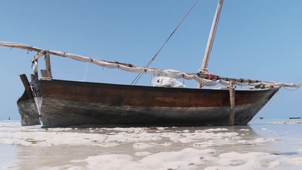 African Traditional Wooden Boat Stranded in Sand on Beach at Low Tide Zanzibar