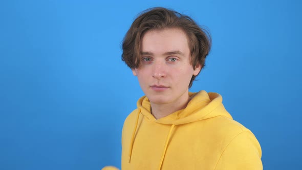 Cheerful Guy Eating Potato Chip Against Blue Background