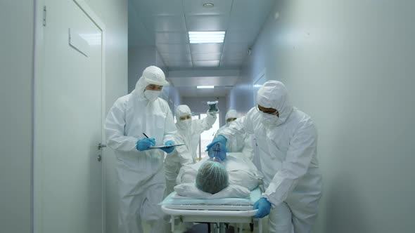 Hospital Workers in Protective Suits Pushing Patient on Gurney