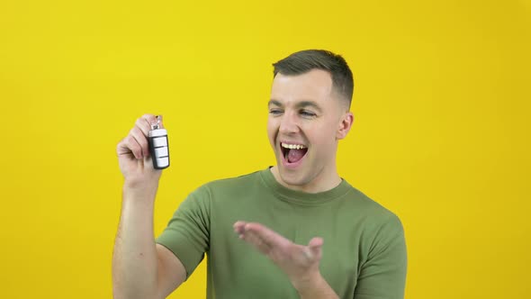 Happy Cheerful Man in a Green Tshirt Happily Raises a Car Key to His Face and Expresses the Joy of