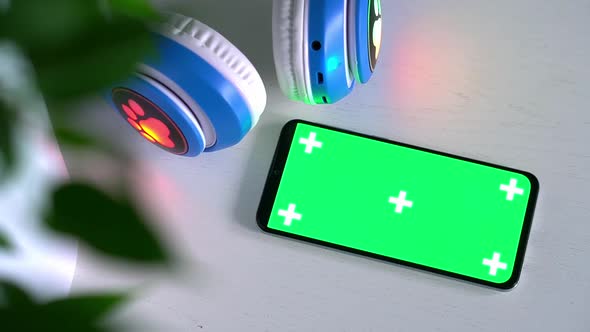 Smartphone with Blank Green Screen Mockup with Kids Wireless Headphones Isolated on Gray Background