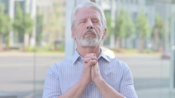 Old Man Praying to God with Folded Hands Outdoor