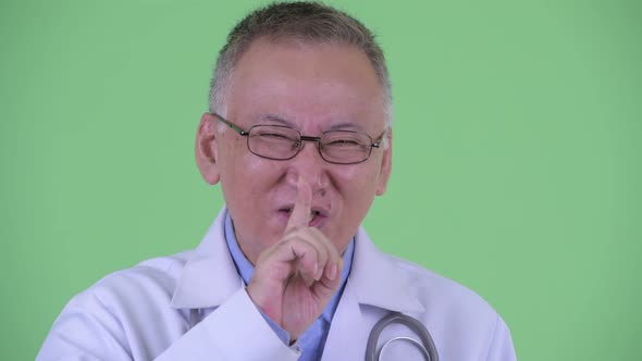 Happy Mature Japanese Man Doctor with Finger on Lips