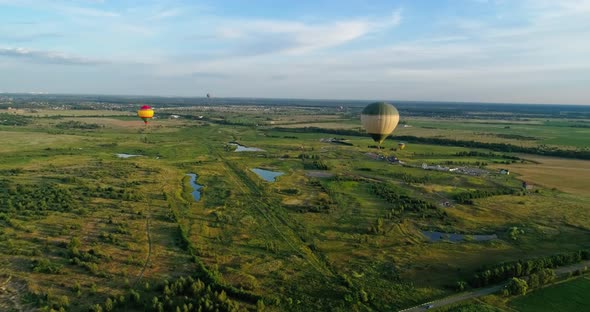 Colorful aerostats among nature. Hot air balloons fly in the sky over fields and lakes in the countr