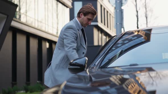 Young Businessman Walks to a Black Car and Sits in the Passenger Seat an Elegant Man in a Suit