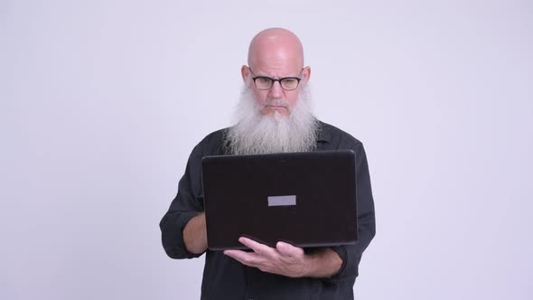 Mature Bald Bearded Man Using Laptop and Looking Shocked