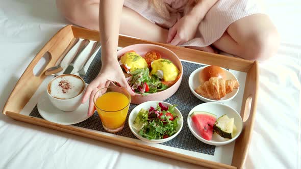 Woman Eating Breakfast in Bed in Cozy Hotel Room