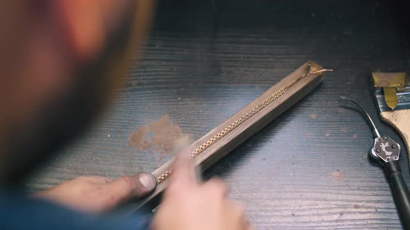 Goldsmith Polishes Bracelet with Rasp on Wooden Part Closeup