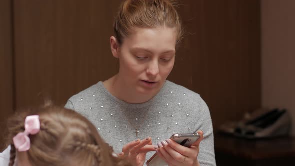 Mother With Smartphone And Daughter Learning