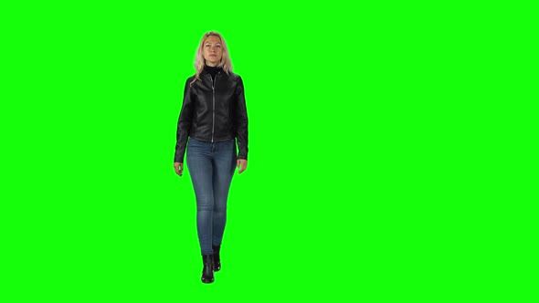 Blonde Girl in Black Leather Jacket, Jeans and Boots Going Against a Green Screen.