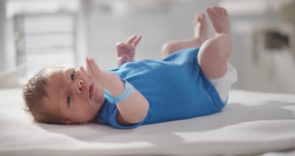 Cute Newborn Boy in Blue Cloth Lying on Bed in Hospital