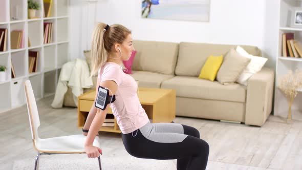 Woman Listening to Music and Doing Triceps Dips with Chair in Home