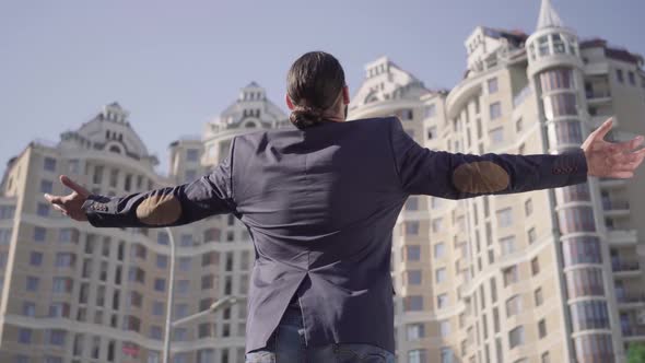 Back View of Adult Middle Eastern Man with Black Ponytail Raising Hands and Gesturing. Successful