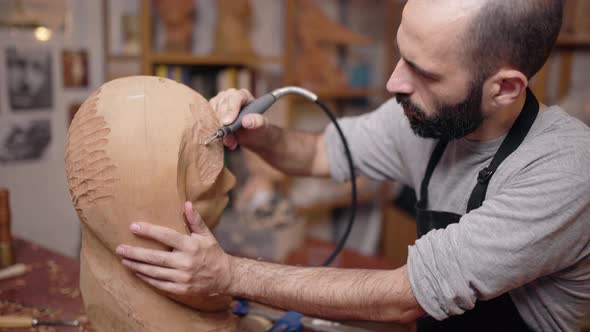 Craftsman carving wooden sculpture in workshop