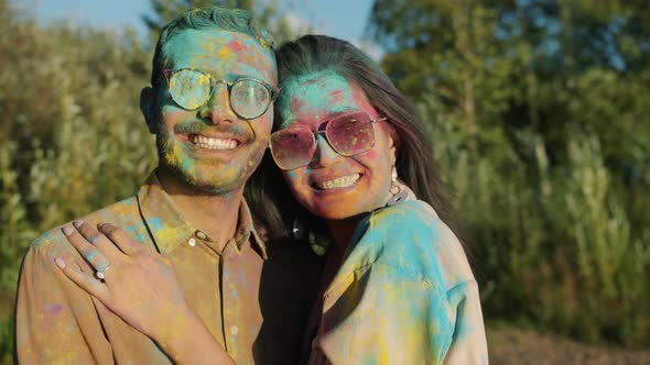 Husband and Wife Covered with Colorful Paint Smiling Enjoying Holi Festival Outdoors