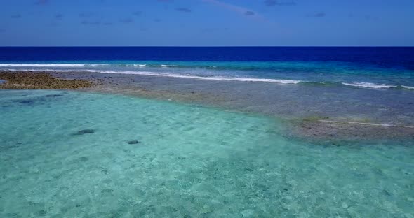 Beautiful fly over travel shot of a sandy white paradise beach and turquoise sea background in vibra