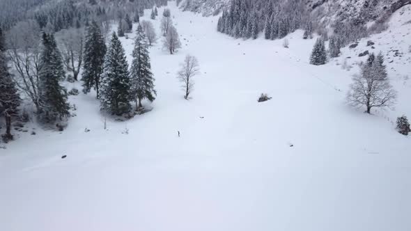 Beautiful big winter mountain scenery in Switzerland. A guy is walking through the deep snow.