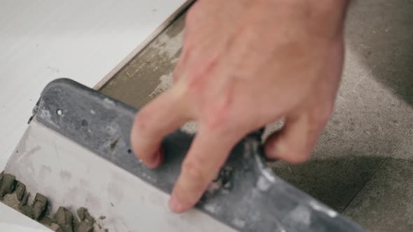 Builder Laying Tiles Using Cement and Spatula Closeup Man Installing Ceramic Slabs on Floor and