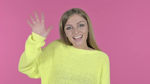 Attractive Young Girl Waving at Camera, Pink Background