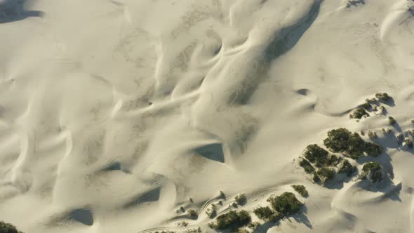 Drone aerial looking down on large expansive sandy dunes in sunlight