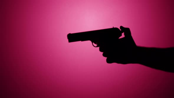 Man Holding Gun Closeup Shadow Silhouette of Hand with Pistol on Pink Neon Background