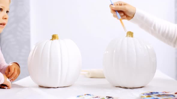 Step by step. Mother and daughter decorating Halloween craft pumpkin with unicorn theme.