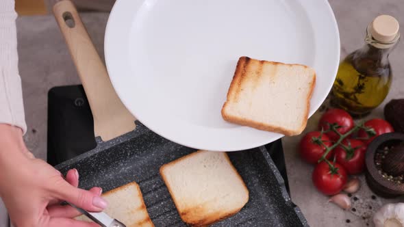 Woman Putting Toasted Bread From Grill Frying Pan Onto White Ceramic Plate