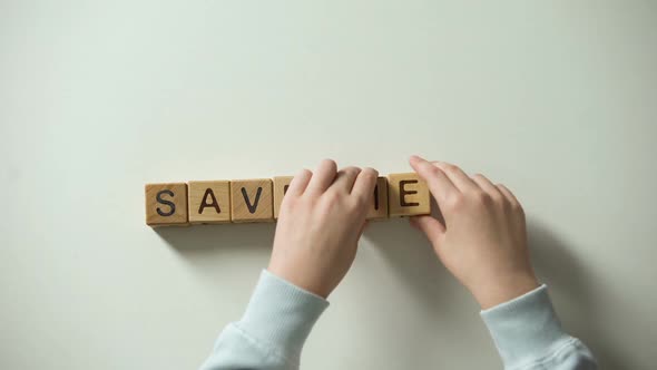 Childs Hand Putting Heart Sign and Save Me Phrase Made of Wooden Cubes