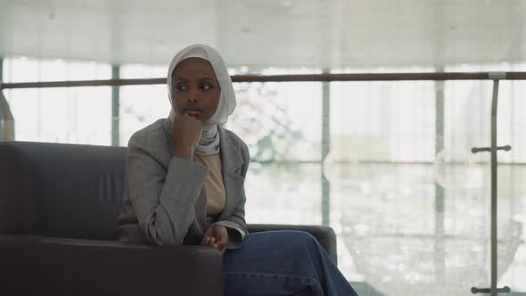 Thoughtful Black Woman in Hijab Waits for Partners in Office