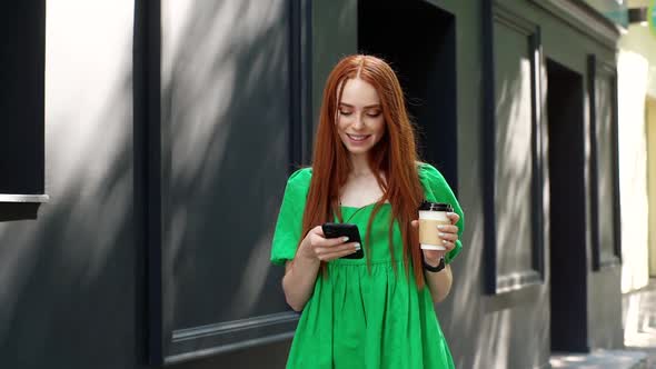 Happy Attractive Young Woman Using Browsing Mobile Phone Holding Cup of Coffee and Looking Around