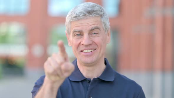 Outdoor Portrait of Middle Aged Man Pointing Finger and Inviting