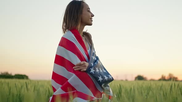 Portrait of Happy Mixed Race Young Woman Standing in Wheat Field Wrapped in USA National Flag