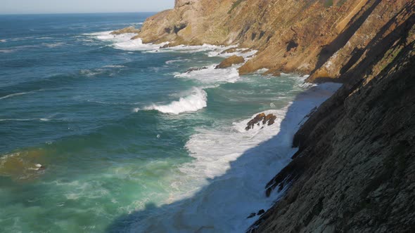 Tilt-up shot of waves crashing into cliffs of Mossel Bay, South Africa