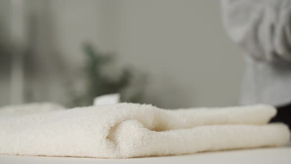 Young Woman Putting Washed Dry Clean Towels on Iron Board Preparing for Ironing