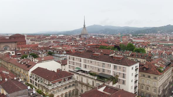 Colorful rooftops of Turin with Mole Antonelliana building in front, aerial ascend view