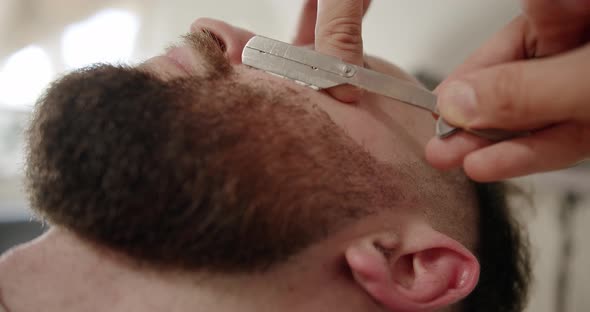 Professional Barber Shaves Customer Beard with Straight Razor