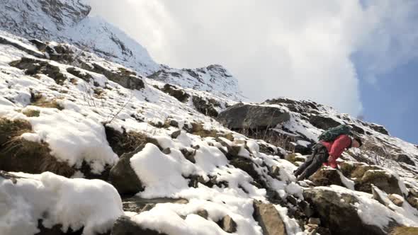 Hiker Climbing Snowy Rocks On Mountain