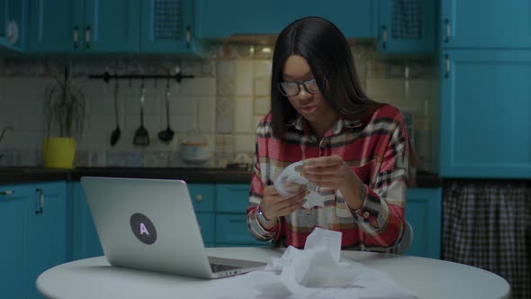 Young African American Woman Holding Big Store Receipts in Hands Complaining Looking at Laptop