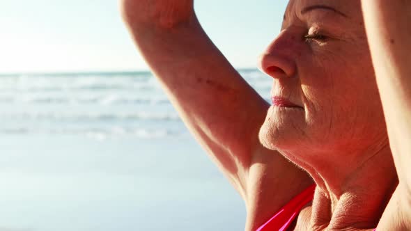 Senior woman doing yoga at beach