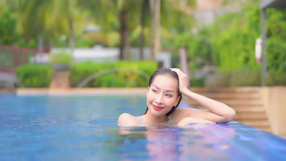 Young asian woman enjoy around outdoor swimming pool for leisure