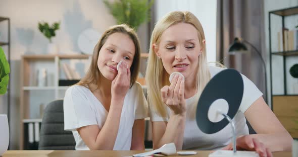 Mother with Her Teen Daughter Doing Facial Procedures Using Cotton Pads in the Morning