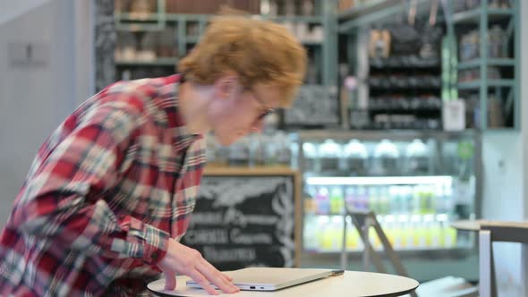 Young Redhead Man Coming Back and Opening Laptop 