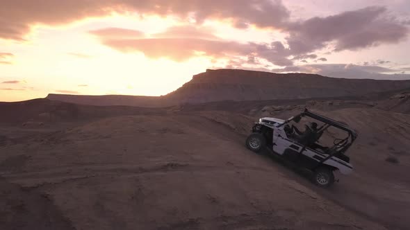 Aerial panning view of OHV driving over dirt hill in the desert