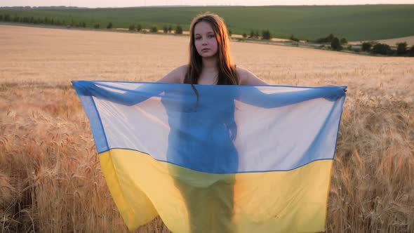 Pray for Ukraine. Child with Ukrainian flag in wheat field.